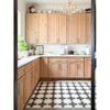 A bright kitchen with light wood cabinets, white counters, and a Spicher and Company Pattern 23 Coptic vinyl floorcloth.