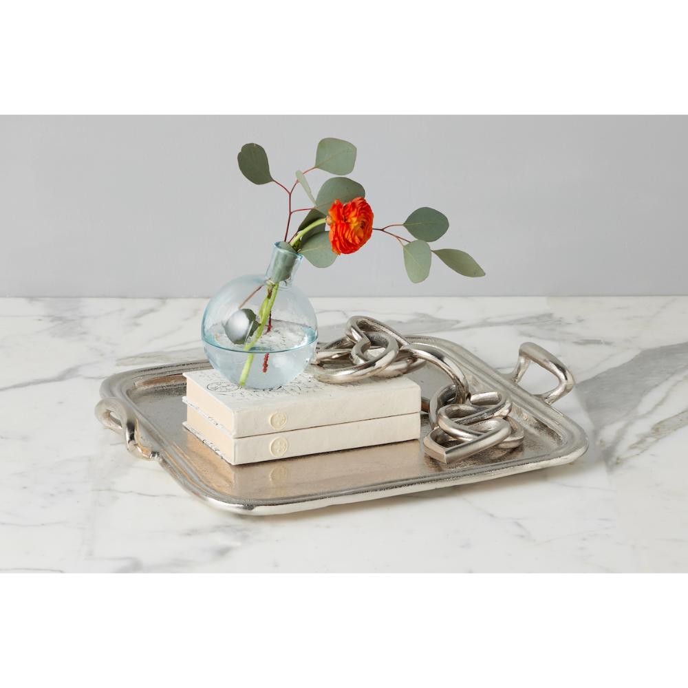 Decorative tray with books and a small vase with flowers on a marble surface.