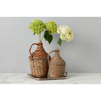 Two wicker bottles with flowers on a marble surface against a gray background