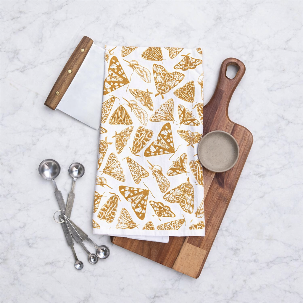 Cooking utensils with a Muse Textiles Flour Sack Moths Kitchen Towel arranged on a marble countertop.
