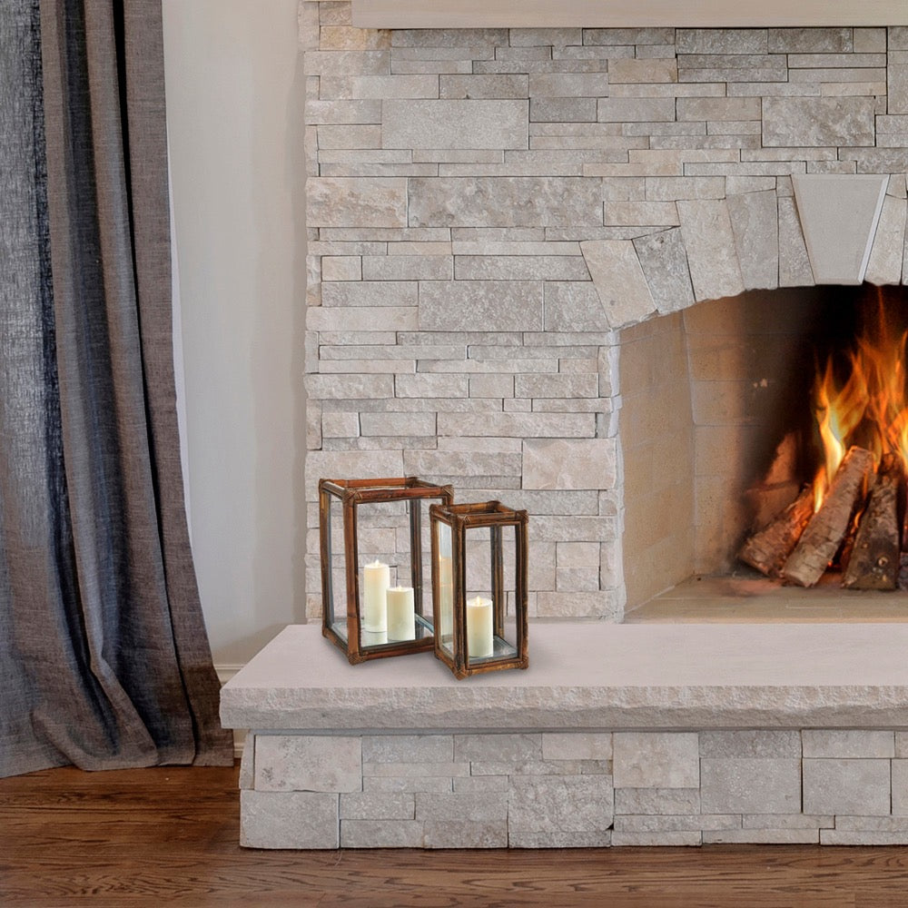 Fireplace with stone surround and lit candles in lanterns on a stone hearth.