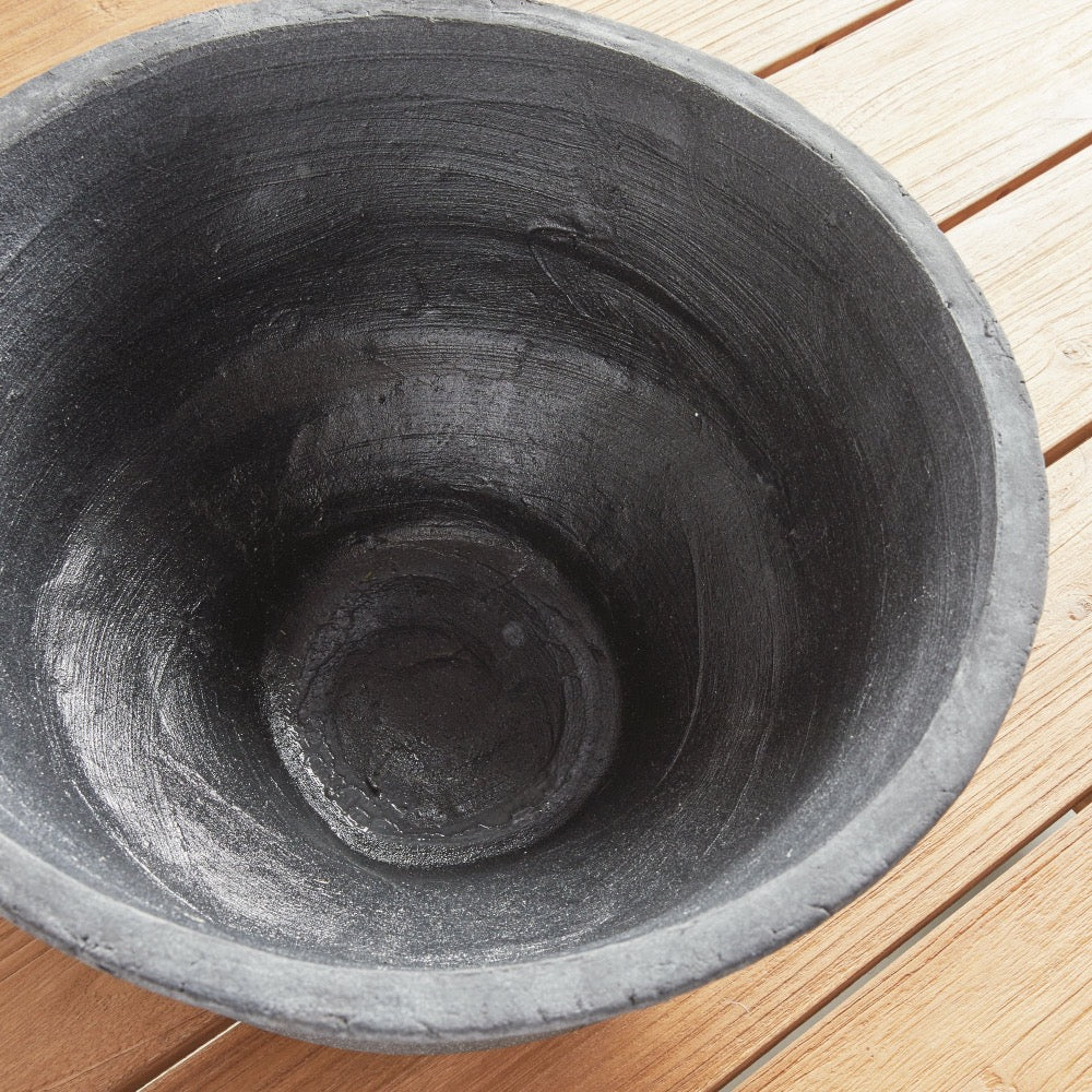 Close-up of a dark gray concrete pot on a wooden surface