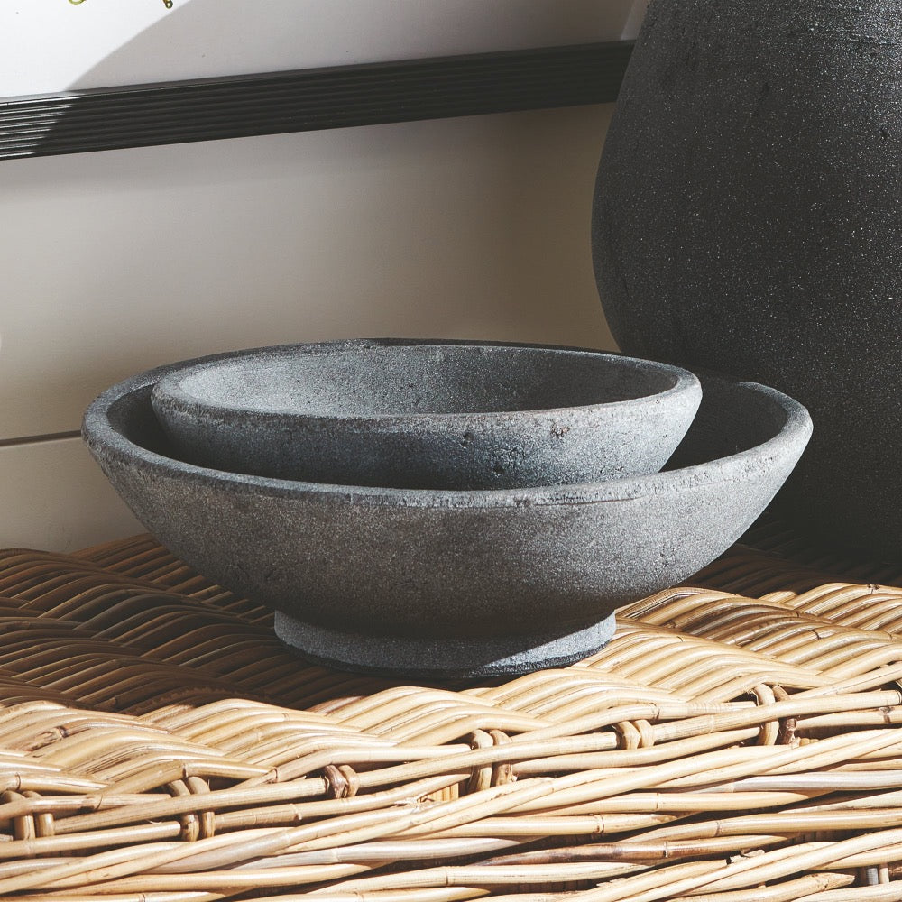 Two dark terracotta bowls on a woven surface with a neutral background