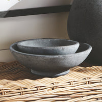 Two dark terracotta bowls on a woven surface with a neutral background