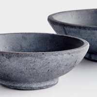Two dark gray terracotta bowls on a light background