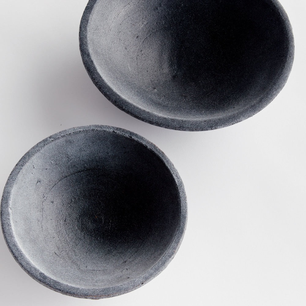 Two dark gray terracotta bowls on a light gray background