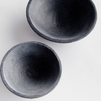 Two dark gray terracotta bowls on a light gray background