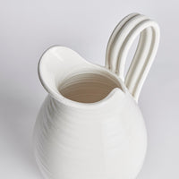 White ceramic pitcher with a handle on a light gray background