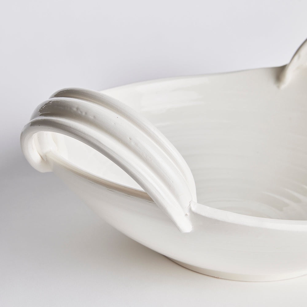 Close-up of a white ceramic bowl with a white handle on a light gray background