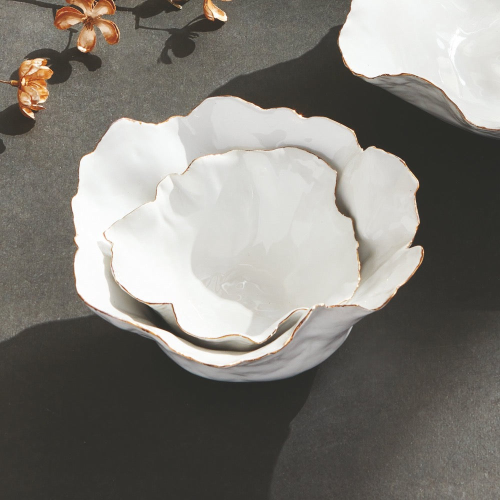 White ceramic bowl with gold rim on a dark surface