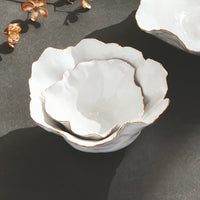White ceramic bowl with gold rim on a dark surface