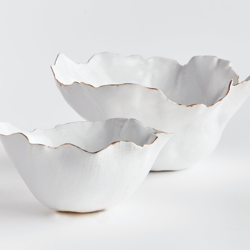 Two white ceramic bowls with ruffled edges on a light gray background