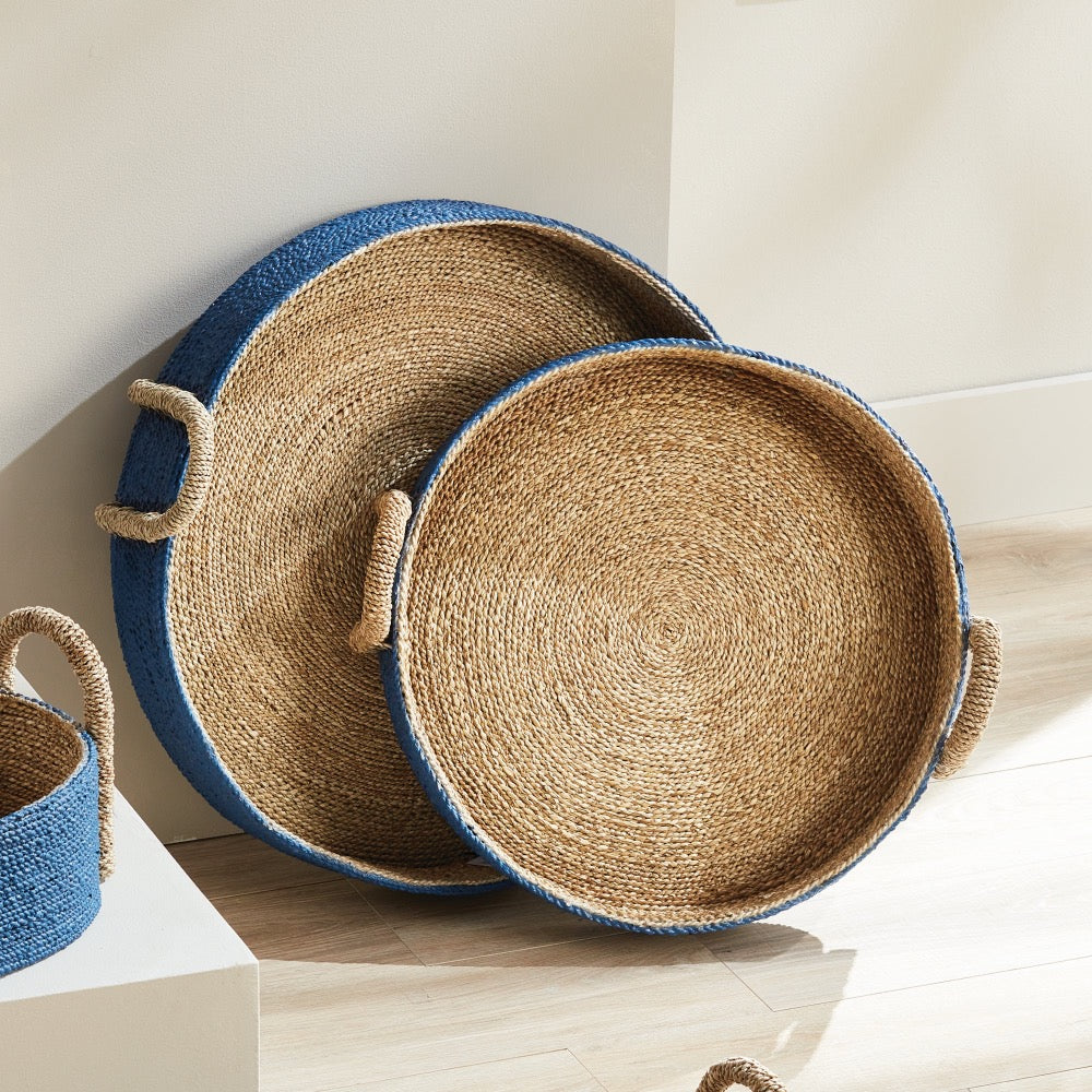 Set of woven trays with blue exterior on a light wooden surface