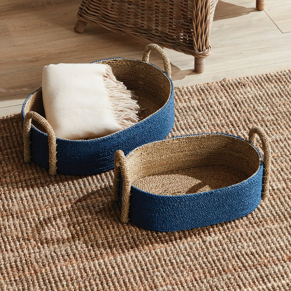 Two woven baskets with handles on a textured rug