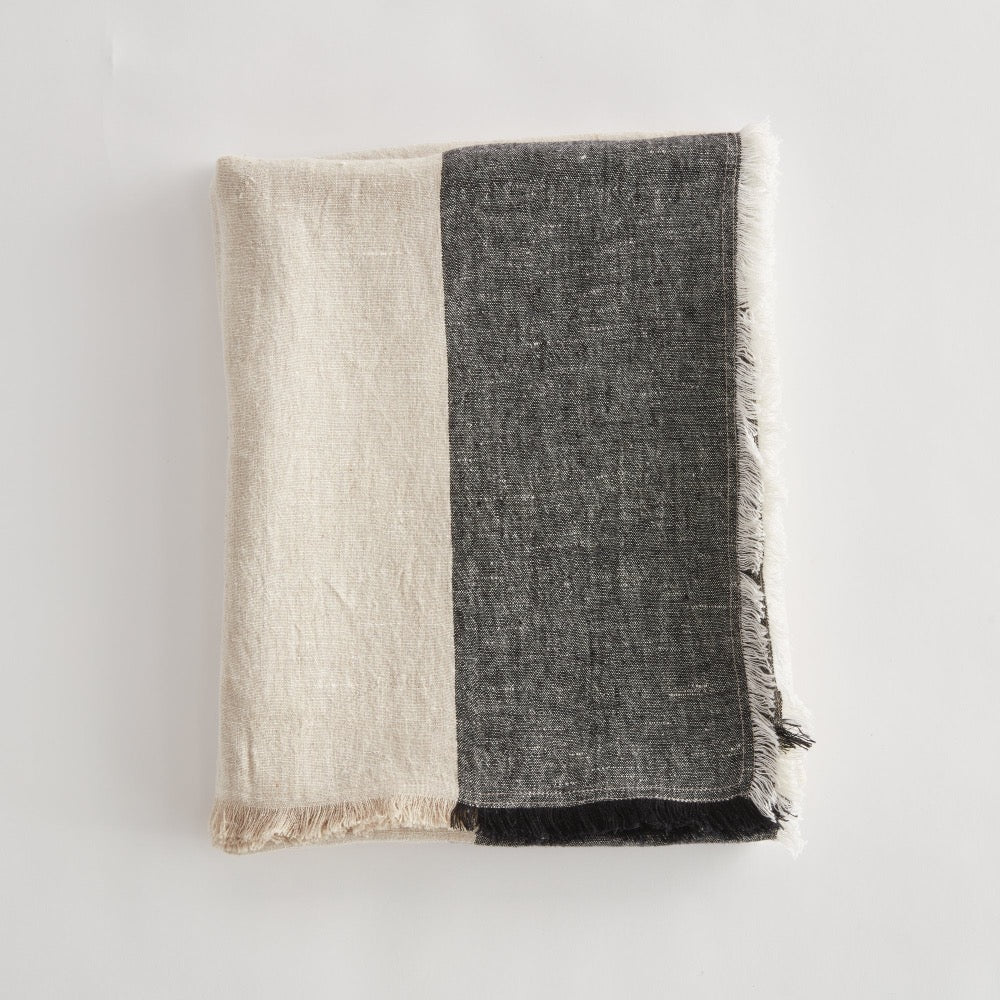 Two tone throw, beige and black, on a light gray background.