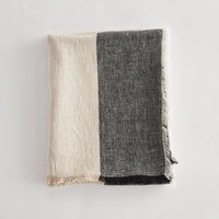 Two tone throw, beige and black, on a light gray background.