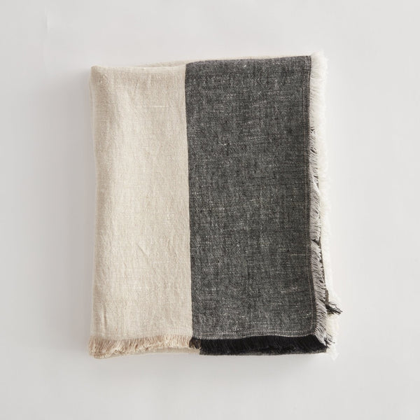 Two tone throw, beige and black, on a light gray background.