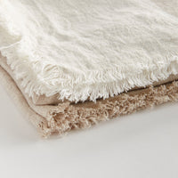 Two tone textured throw blankets with fringes on a light background
