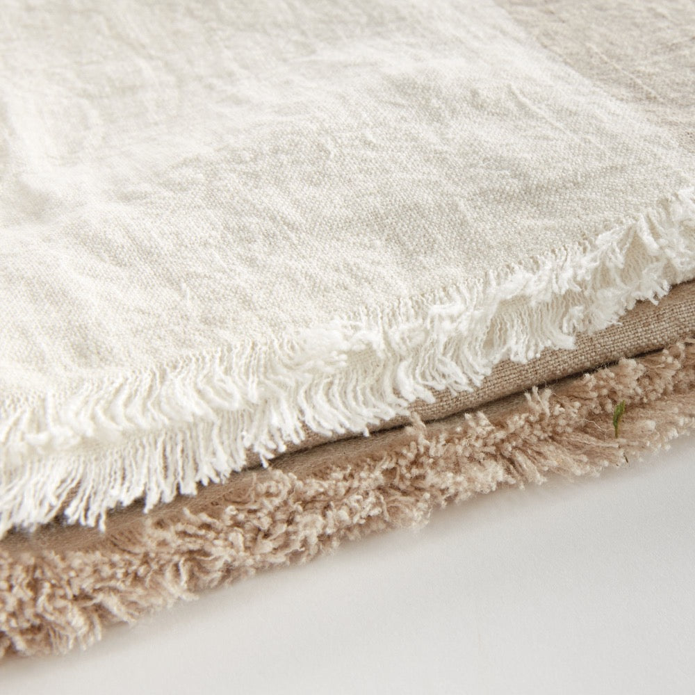 Close-up of two tome throw with fringes on a light background