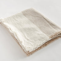 Beige and white striped blanket on a light gray background