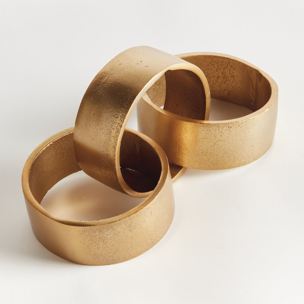 The Napa Home & Garden Corbin Round Chain Sculpture features three interlinked gold rings on a white background.