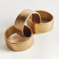 The Napa Home & Garden Corbin Round Chain Sculpture features three interlinked gold rings on a white background.