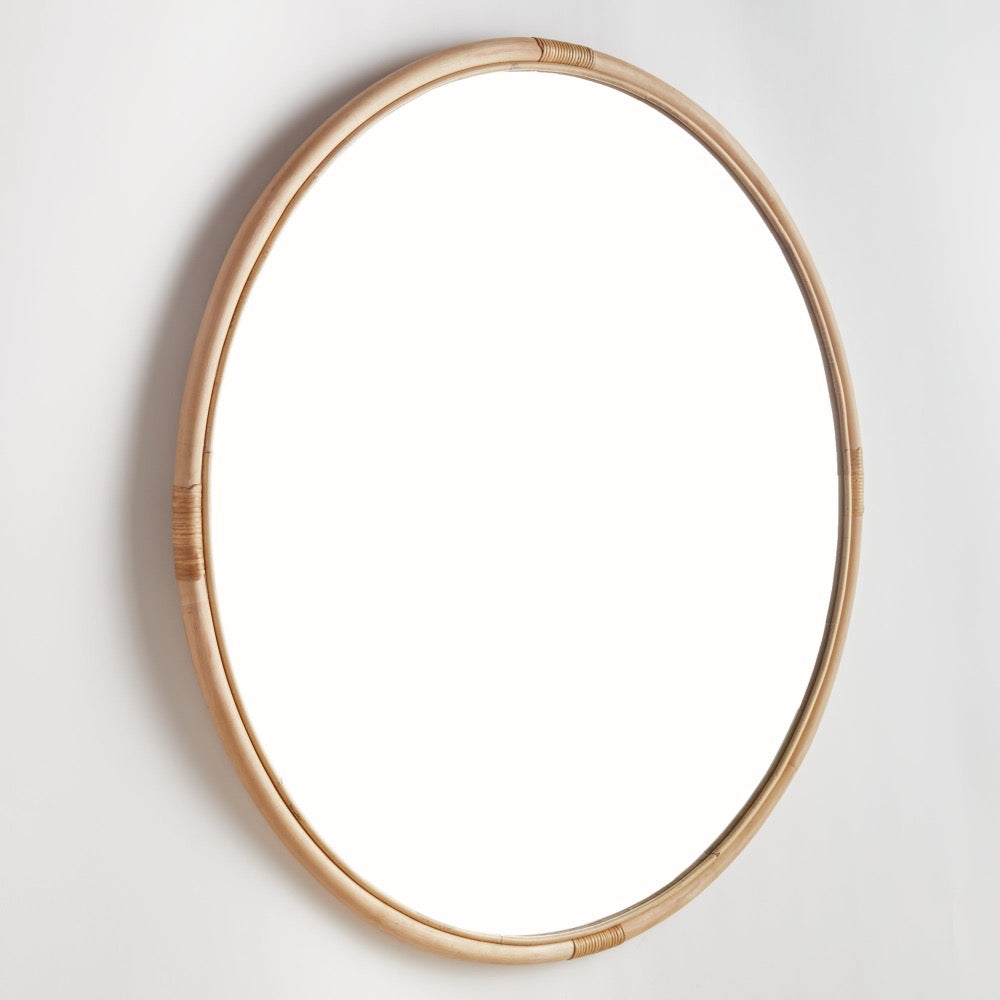 Round mirror with a rattan frame on a white wall
