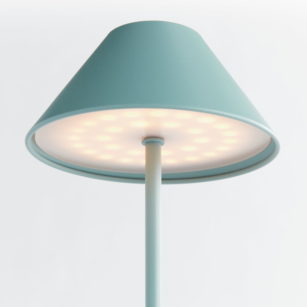 Table lamp with a teal shade on a light gray background