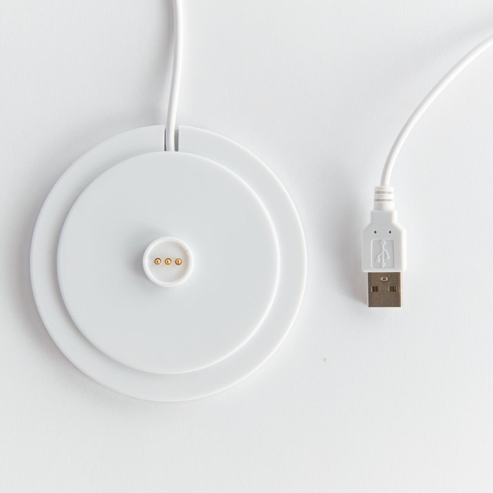 White wireless charging pad with USB cable on a light gray background