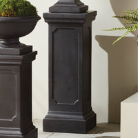 The Fibreclay Chambers Pedestal by Napa Home & Garden features an antique black finish beside a concrete planter and greenery.