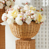Wicker planter with white and pink flowers against a white wall
