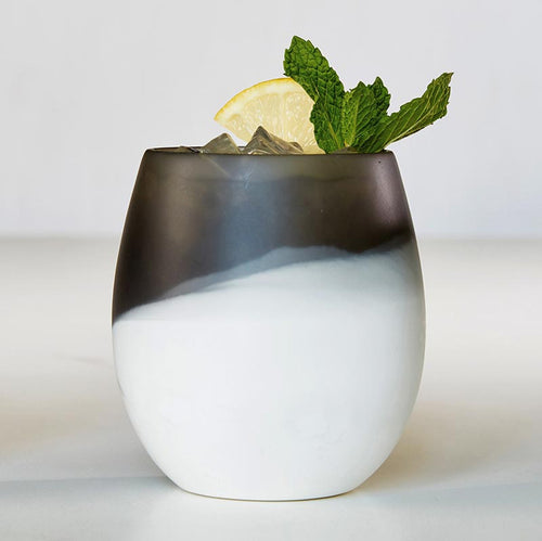 A Santa Barbara Design Studio resin two tone stemless wine glass with ice, lemon slice, and mint leaves.