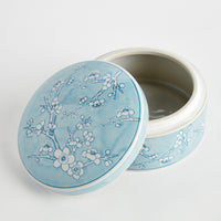 Round ceramic container with floral design on a light blue background
