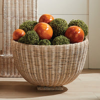 Decorative basket with green and orange spherical ornaments on a wooden floor.