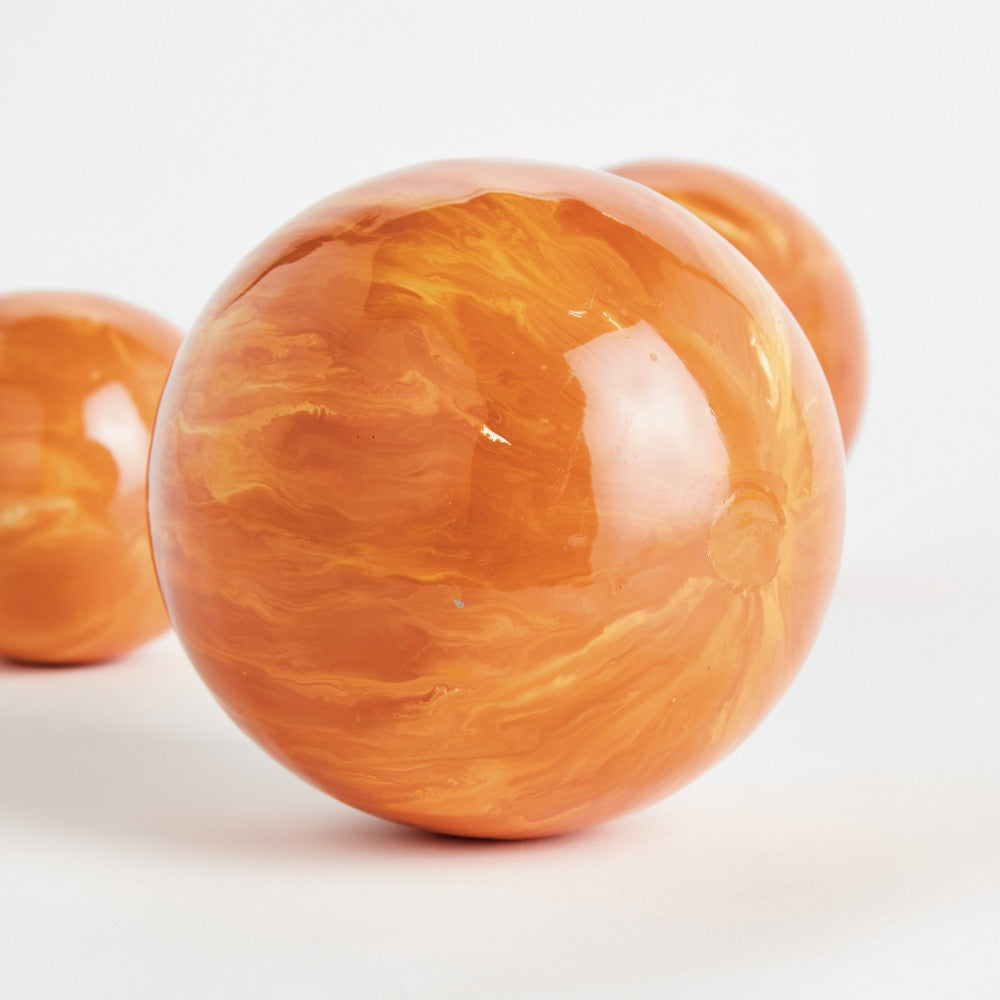 Close-up of a glossy orange sphere on a white background