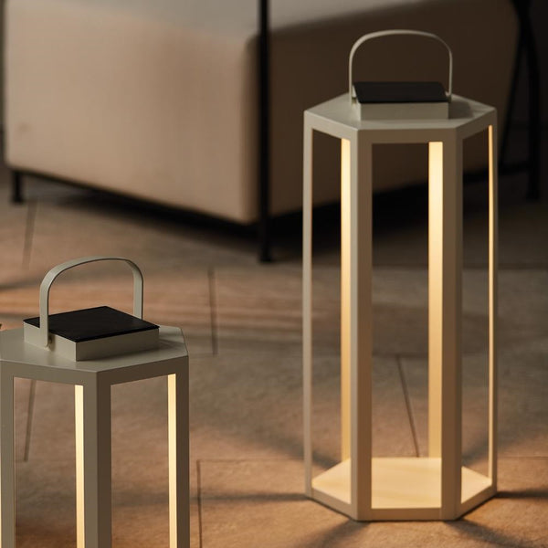 Two hexagonal outdoor lamps with handles on a wooden floor.