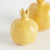 Two yellow ceramic pomegranate-shaped containers on a white background