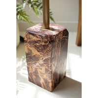 Marble-textured lamp base with bronze fixture on a light surface.