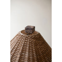 Woven basket with a wooden block on top against a plain background
