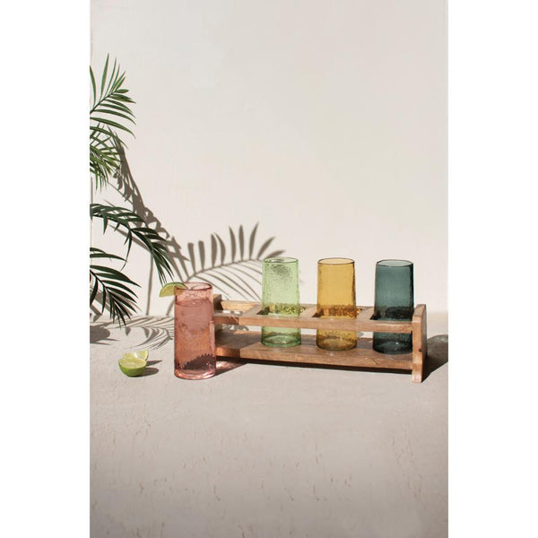 Set of colorful glass tumblers on a wooden stand with a leafy background