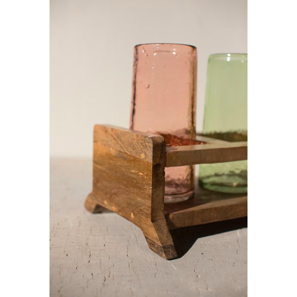 Wooden candle holder with two glass candles on a light surface.
