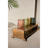 Wooden candle holder with colorful glass candles on a neutral background