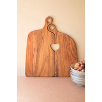Wooden cutting board with heart-shaped hole on a beige surface