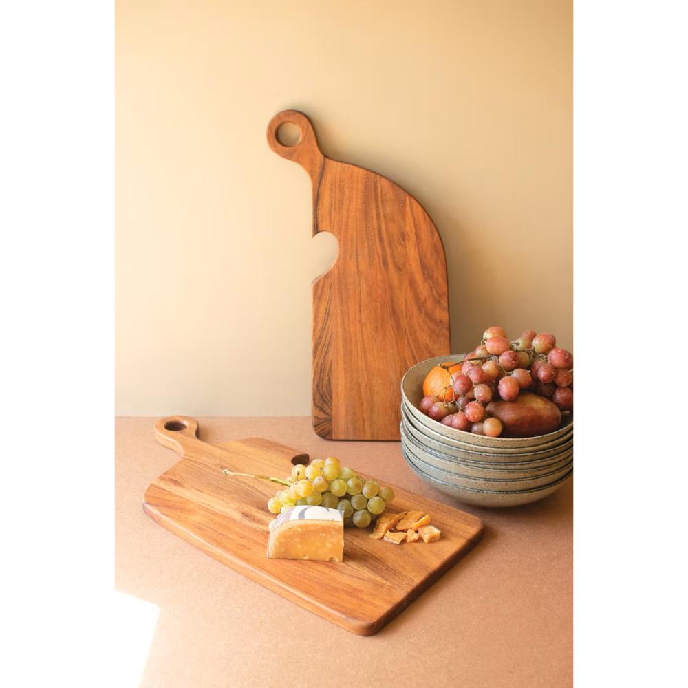 Wooden cutting board with a bowl of grapes on a beige surface