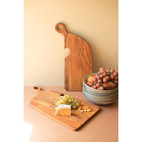 Wooden cutting board with a bowl of grapes on a beige surface