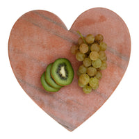 Heart-shaped stone with sliced kiwi and grapes on a white background