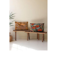 Two decorative pillows on a wooden bench against a plain wall.