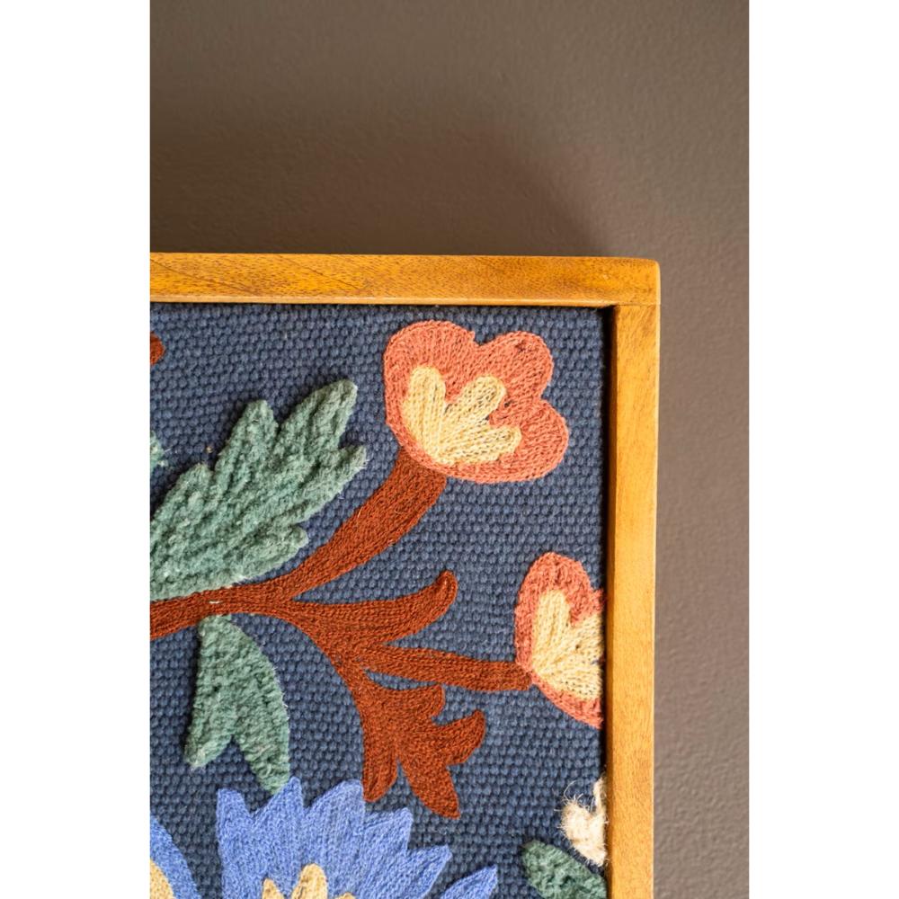 Floral embroidered design on fabric with wooden frame against a dark background