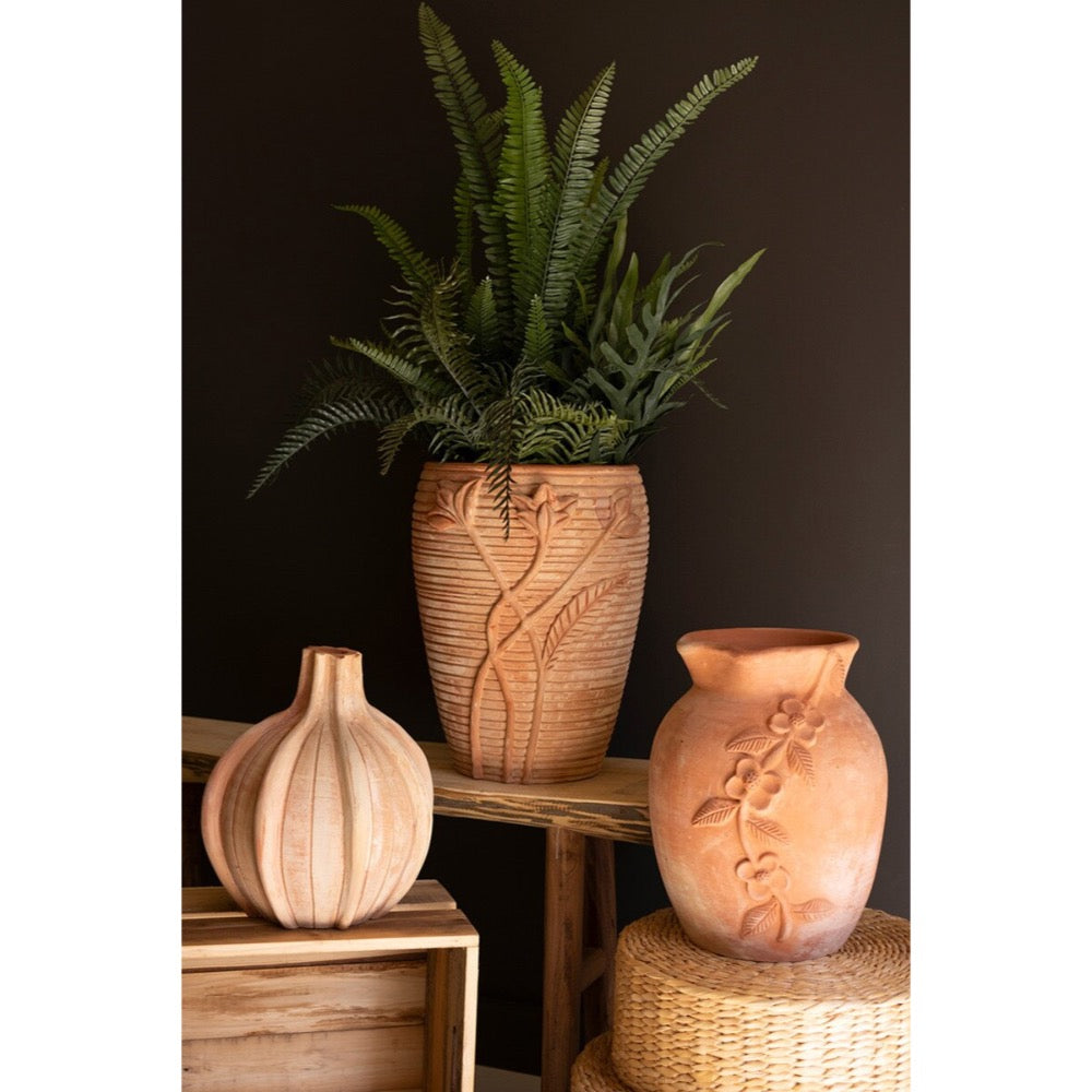 Three wooden vases with floral carvings on a dark background