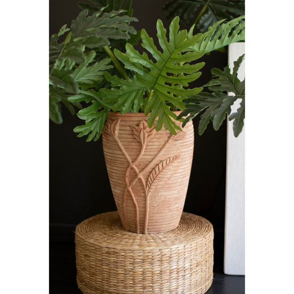 Terracotta vase with a plant on a dark surface